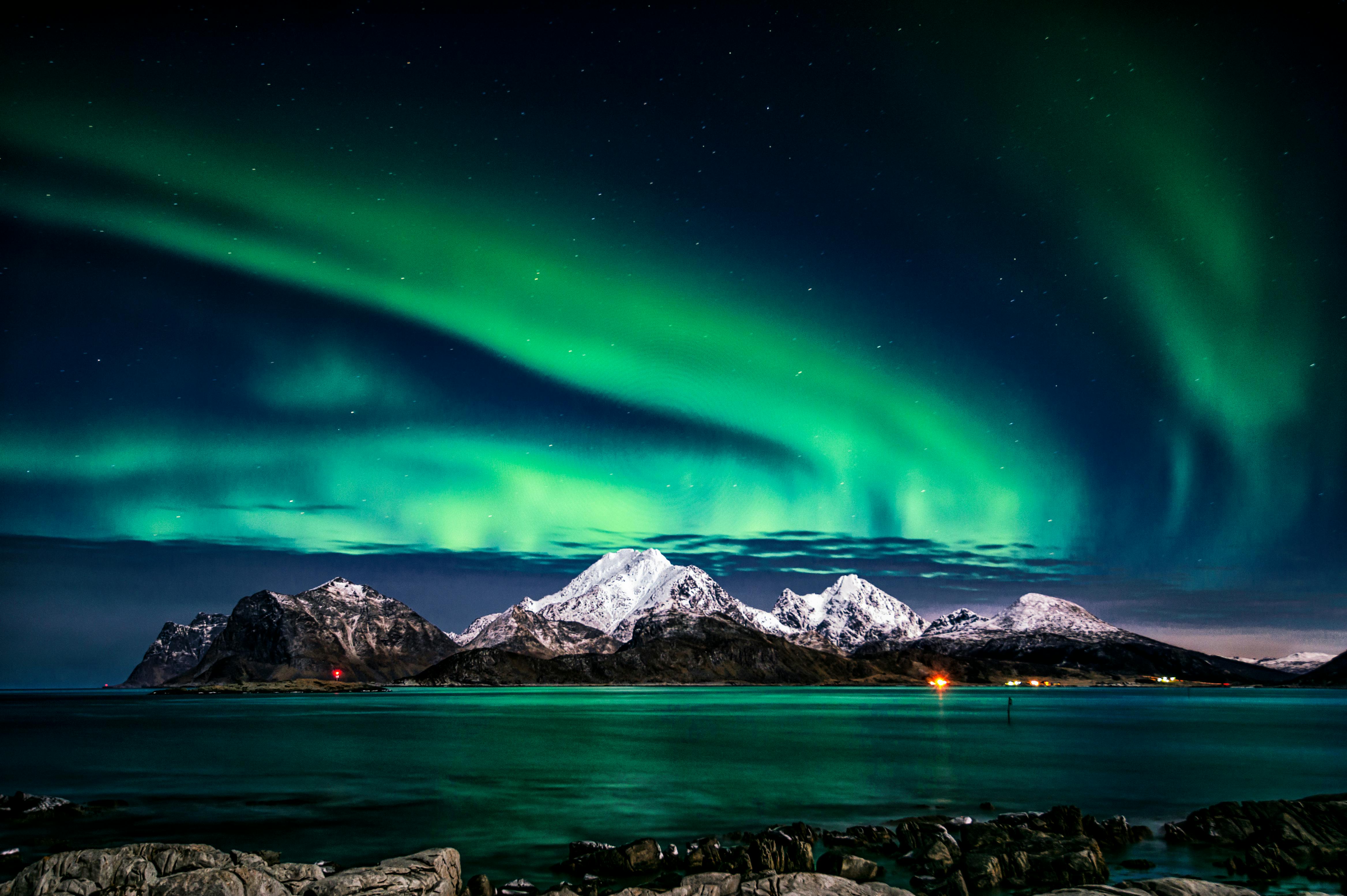 Aurora Borealis dancing over snow-covered mountains.